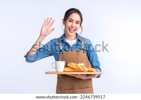 young asian waitress barista wearing apron hand hold bread and coffee drink on wooden tray smiling warm welcome invite customer to her coffee shop studio shot on white background