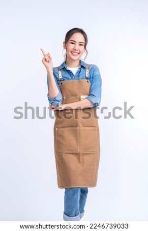 happiness smiling asian young adult female woman wearing apron uniform hand gesture finger point up ,young asia woman barista look at camera studio shot on white background Royalty-Free Stock Photo #2246739033