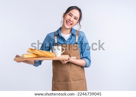 young asian waitress barista wearing apron hand hold bread and coffee drink on wooden tray smiling warm welcome invite customer to her coffee shop studio shot on white background Royalty-Free Stock Photo #2246739045