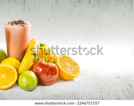 healthy fruit smoothie glass with fruit around it on subtle wood texture on white background with copy space