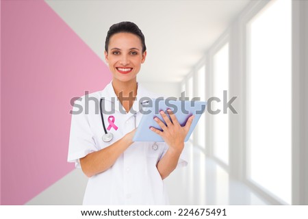 Pretty nurse using tablet pc against modern white and pink room with window