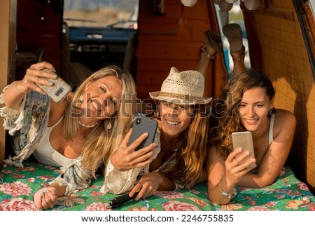 Horizontal photo of three beauty friends taking selfie with the mobile inside a camper van