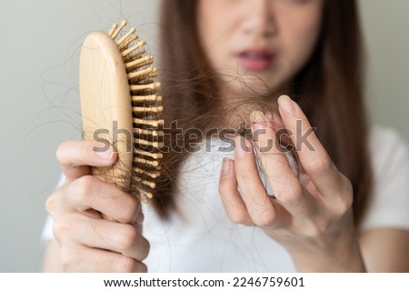 Close-up young woman brushing her hair and have many hair loss on the comb Royalty-Free Stock Photo #2246759601