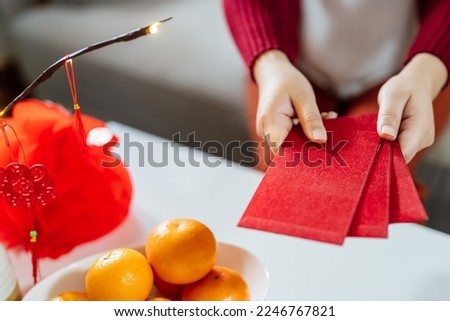 Asian Woman giving red envelope for Lunar New Year celebrations. Hand hold red packet. Royalty-Free Stock Photo #2246767821