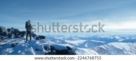 Hiker photographer in snowy mountains Royalty-Free Stock Photo #2246768755