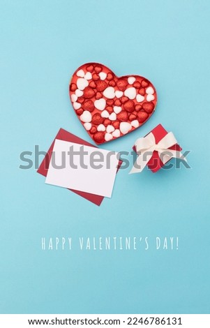Valentines day greeting card with Red white glitter hearts, gift box and empty craft envelope on blue background. Flat lay, top view, copy space. Concept for Valentines, Birthday, Woman or Mothers Day