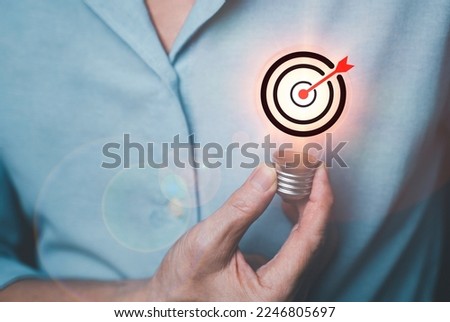 hand of a man hold light bulb with heart of target And he shows commitment to achievement. The goal of inspiration from leadership. marketing and management idea concept.