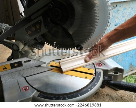 marking and cutting wooden planks on a miter saw, an angle saw in a carpenter's workshop while working with wood panels, trimming the ends of floor skirting boards on a miter saw