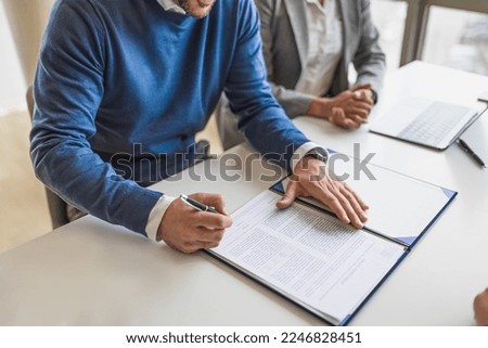 Picture of businessman or entrepreneur in blue sweater, leaving a signature on a document for finance. Royalty-Free Stock Photo #2246828451