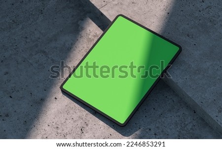 Mockup of black tablet device, lay on a concrete surface, outdoor. Clipping path for display included. 3D rendering. 3D Illustration