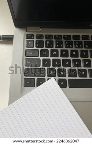 a laptop on the desk with a note book