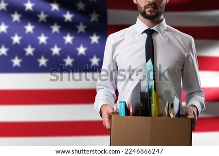 American loses job. Man with box of fired. Office worker near USA flag. Man was fired from job because of crisis. Dismissal of employees in USA companies. Labor market crisis in United States. Royalty-Free Stock Photo #2246866247