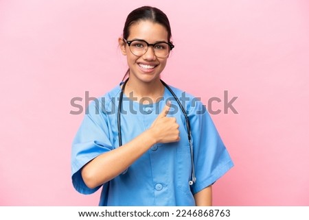 Young nurse Colombian woman isolated on pink background giving a thumbs up gesture