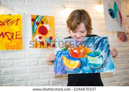 happy child holding his still life painting in his hands