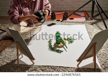 Female photographer taking photo of aloe vera leaf, branches and lotion on this plants on camera at home studio. Beauty and body care content for photostocks, commerce, social networks and advertising