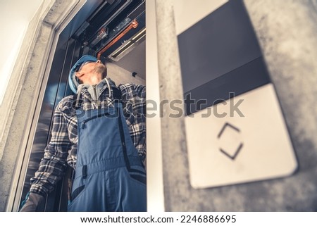 Professional Caucasian Elevator Technician Fixing Lift Doors in Newly Build Residential Building. Lifting Machine Maintenance. Royalty-Free Stock Photo #2246886695