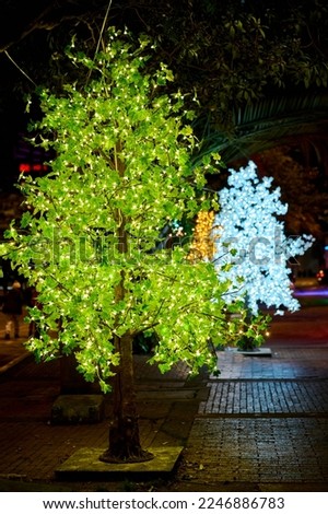  plastic trees illuminated with led bulbs in the middle of the park formed in rows. night decoration in the planetarium of Bogota in Colombia. plastic leaves glowing. colorful trees glowing in the nig