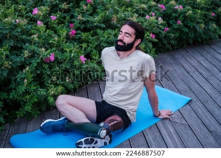 Young man with prosthetic leg doing stretching after an afternoon of outdoor training