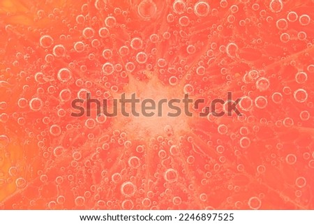 Close-up of a grapefruit slice in liquid with bubbles. Slice of red ripe grapefruit in water. Close-up of fresh grapefruit slice covered by bubbles. A colourful macro shot of a juicy red grapefruit.  Royalty-Free Stock Photo #2246897525