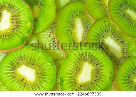 Close-up view of the green kiwi fruit slices in water background. Texture of cooling fruit drink with macro bubbles on the glass wall. Flat design. Horizontal image.