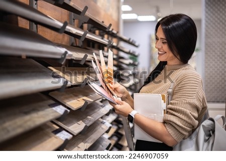 Happy brunette female interior designer choosing flooring tile color texture samples at store shop. Woman architect choice floor and wall finishing material for architecture and construction industry Royalty-Free Stock Photo #2246907059