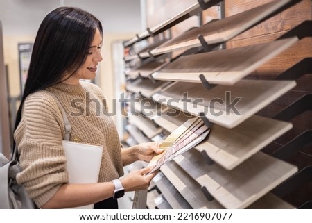 Happy brunette female interior designer choosing flooring tile color texture samples at store shop. Woman architect choice floor and wall finishing material for architecture and construction industry Royalty-Free Stock Photo #2246907077