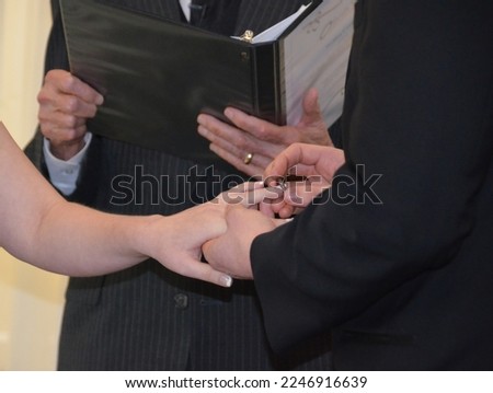 Wedding rings being exchanged as the groom places a ring on the brides hand.  Picture is of their hands and the ring.