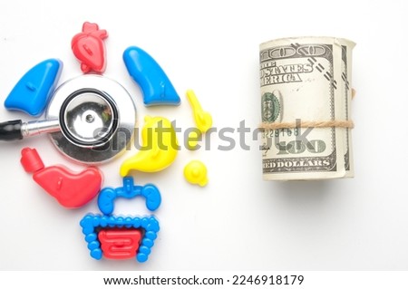 A flatlay picture of toy human organ, stethoscope and roll of fake money. Medical expenses and medicare advantage concept.