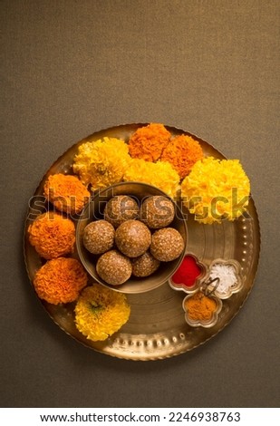 Top view of Pooja Thali with bowl of sesame laddoo, kumkum and marigold flowers. Food and objects for Makar Sankranti festival. Royalty-Free Stock Photo #2246938763