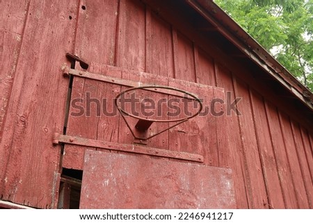 Basketball hoop on an old red barn. Summer season.                                
