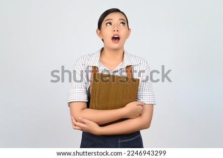 Portrait of young asian woman in waitress uniform holding clipboard and looking up, copy space to insert products for advertisement isolated on white background
