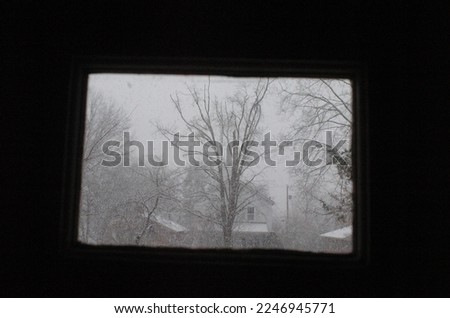 Winter snow storm seen through a window. Window is about one half of the entire frame, centered in the middle of the photo.