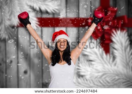 Woman wearing red boxing gloves against festive bow over wood