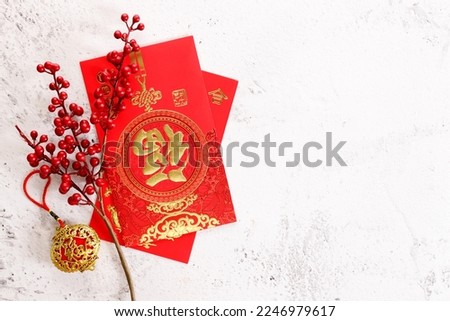 Chinese new year festival decorations with red bags, and red Chinese branch on white marble background. Celebrate Happy Chinese new year background. All Brushscript Texts in Chinese meaning luck.