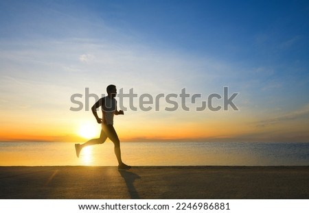 Side view of fitness man jogging on the seaside concrete road with sunrise background. Royalty-Free Stock Photo #2246986881