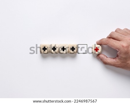 Add value concept. Improvement or addition to something that makes it worth more. Positive thinking or personal growth. Male hand arranges the wooden cubes with plus signs.