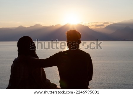 lovers make a heart out of their hands at sunset by the sea silhouette look at the sun