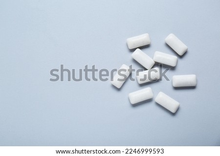 Tasty white chewing gums on light grey background, flat lay. Space for text