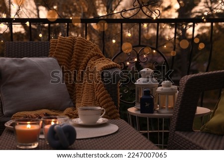 Beautiful view of garden furniture with pillow, soft blanket and burning candles at balcony Royalty-Free Stock Photo #2247007065