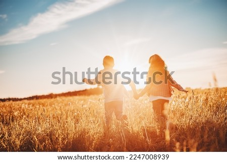 Two children running on the summer field by holding hands. Concept of friendship and family vacation.