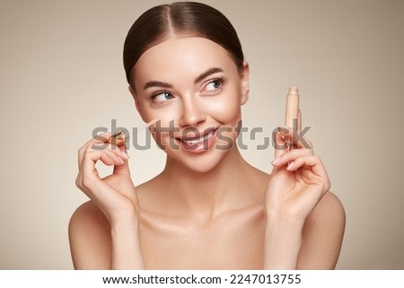 Portrait beautiful young woman with clean fresh skin. Model with foundation makeup bottle. Cosmetology, beauty and spa Royalty-Free Stock Photo #2247013755