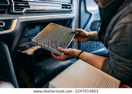 Close up picture of a mechanic changing air filters old for new one in a car.