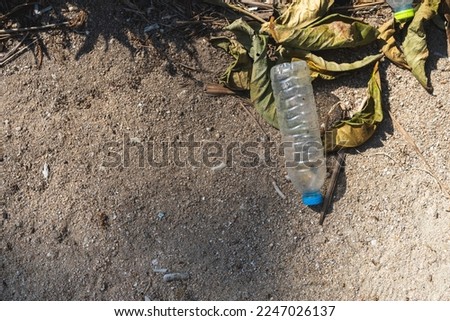 A used and empty plastic bottle discarded on a beach.