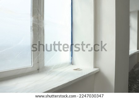 Window covered by plastic film and insulation tape indoors