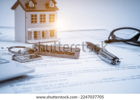 Classic house model, house key with "new homeowner" and calculator on office desk.