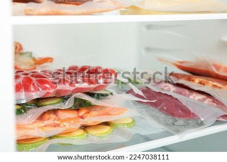 Vacuum bags with different products in fridge, space for text. Food storage Royalty-Free Stock Photo #2247038111
