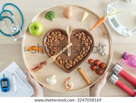 Intermittent fasting IF and keto diet concept with hour clock timer for skipping meal, eating ketogenic food low carb, high fat food, healthy nutritional heart dish with gym exercise for weight loss Royalty-Free Stock Photo #2247038169