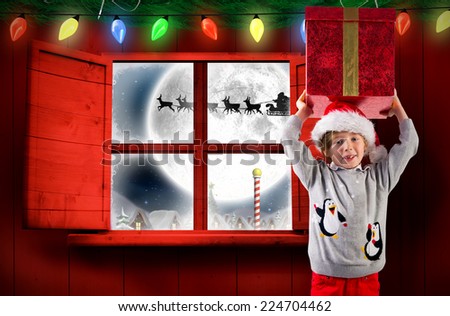 Festive boy holding a gift against santa delivery presents to village
