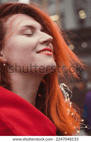 Close up smiling woman with fairy lights on street portrait picture. Closeup side view photography with blurry background. High quality photo for ads, travel blog, magazine, article