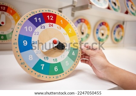 Daylight saving time or Time management concepts. Male hand holding colorful wooden clock on home decoration store display shelf.